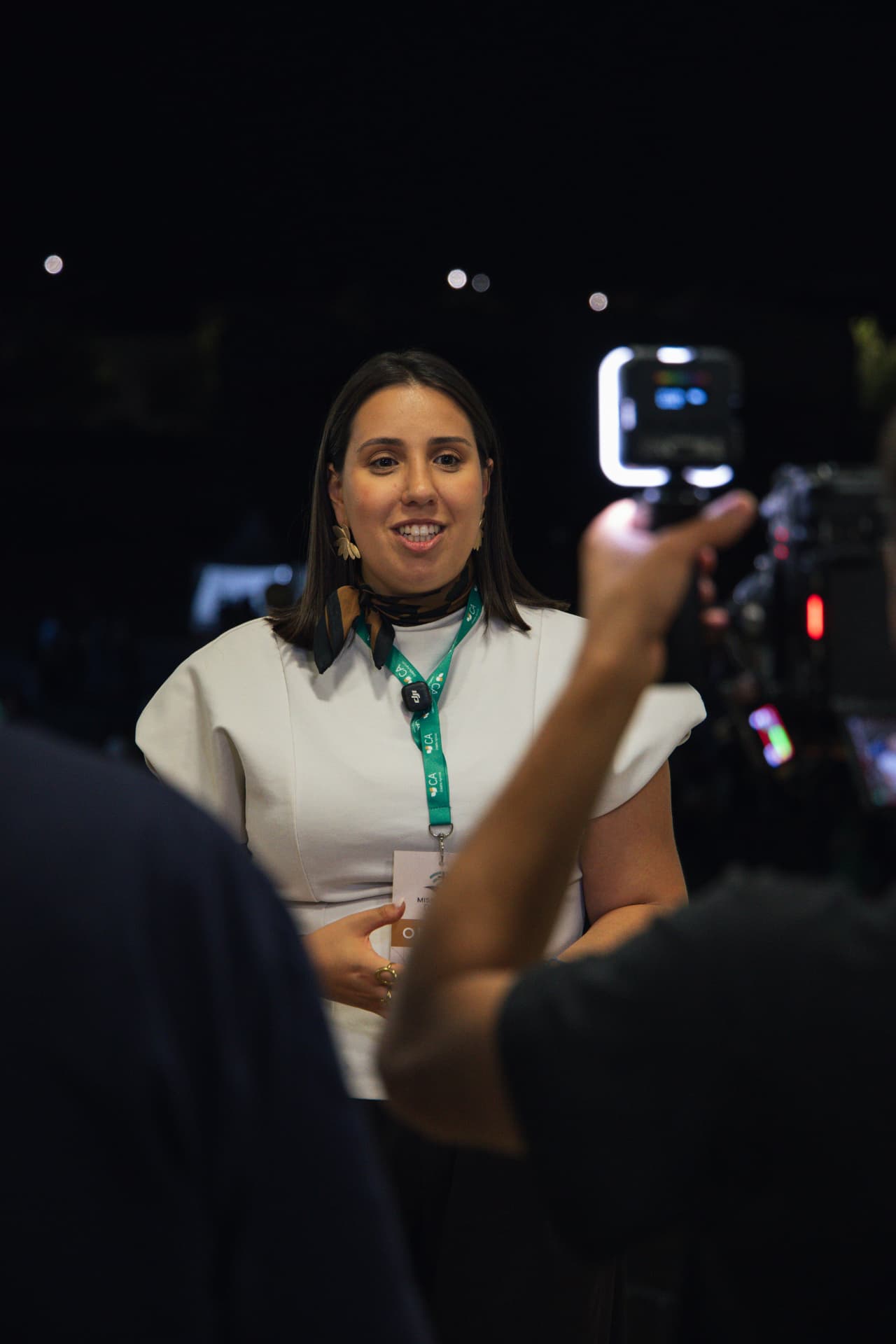 Oradora sorridente responde aos jornalistas no recinto à noite