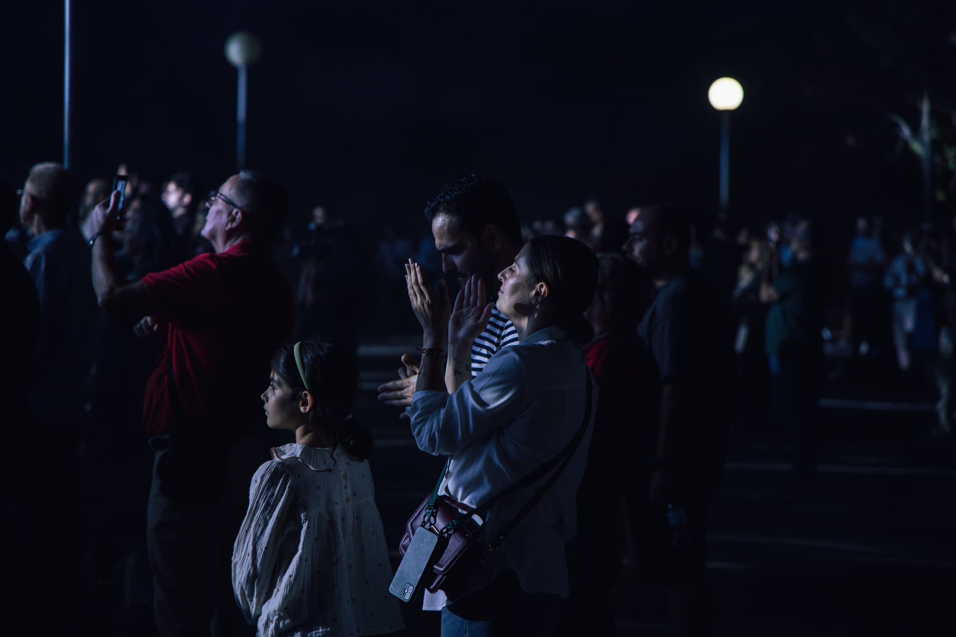 Família em oração no meio da multidão durante a noite