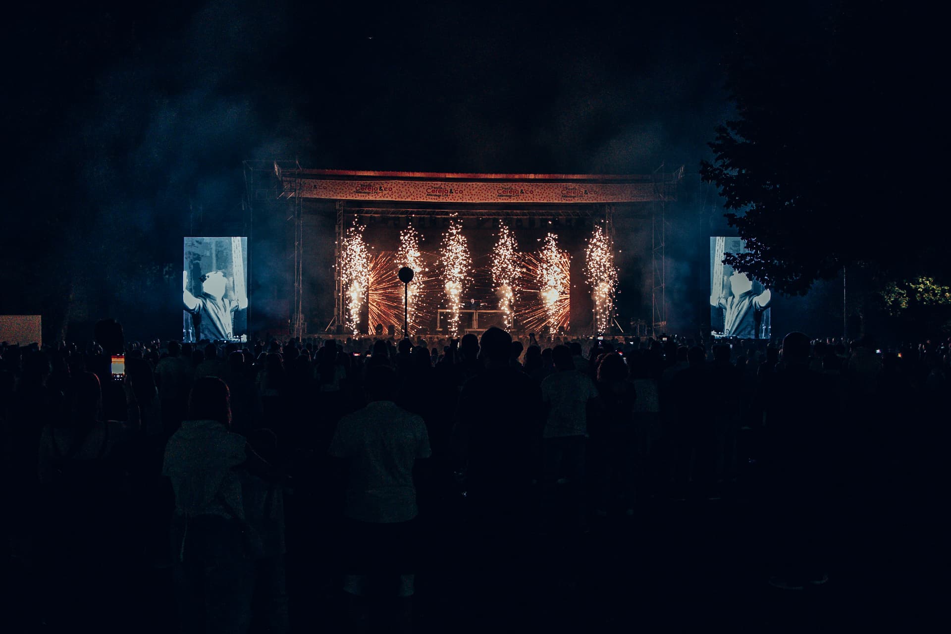 Palco com ecrãs laterais e efeitos de fogo durante a noite
