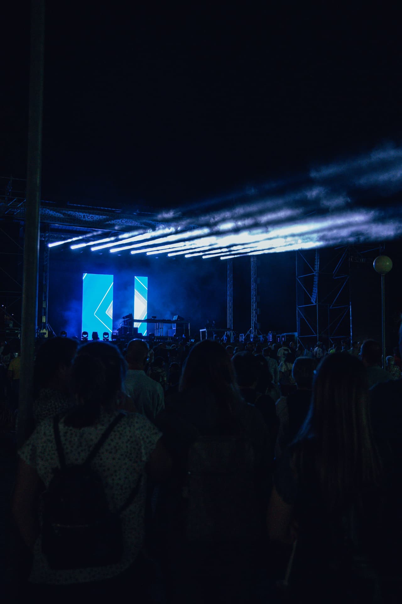 Palco com feixes de luz azul sobre o público à noite