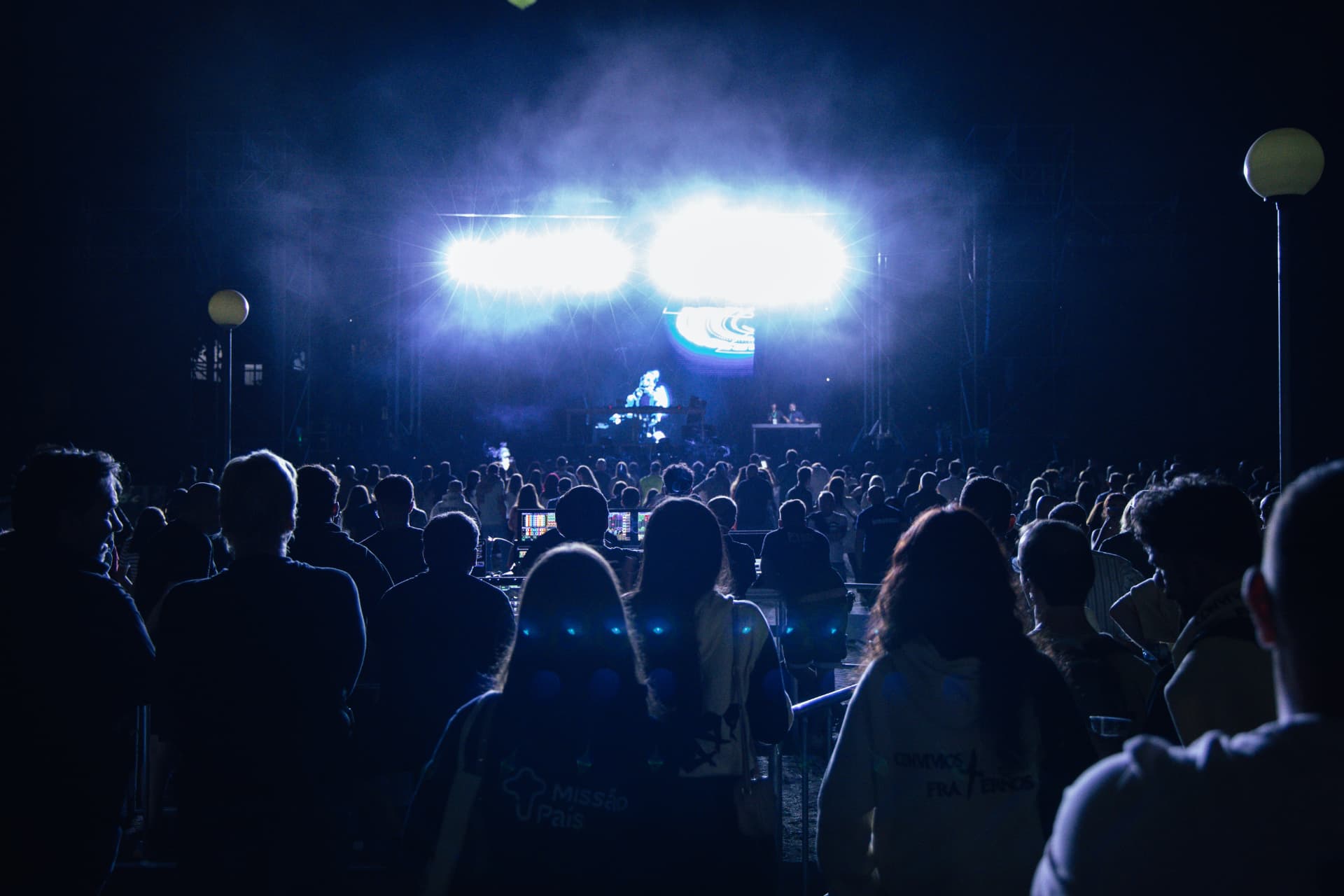 Multidão diante do palco iluminado por focos azuis