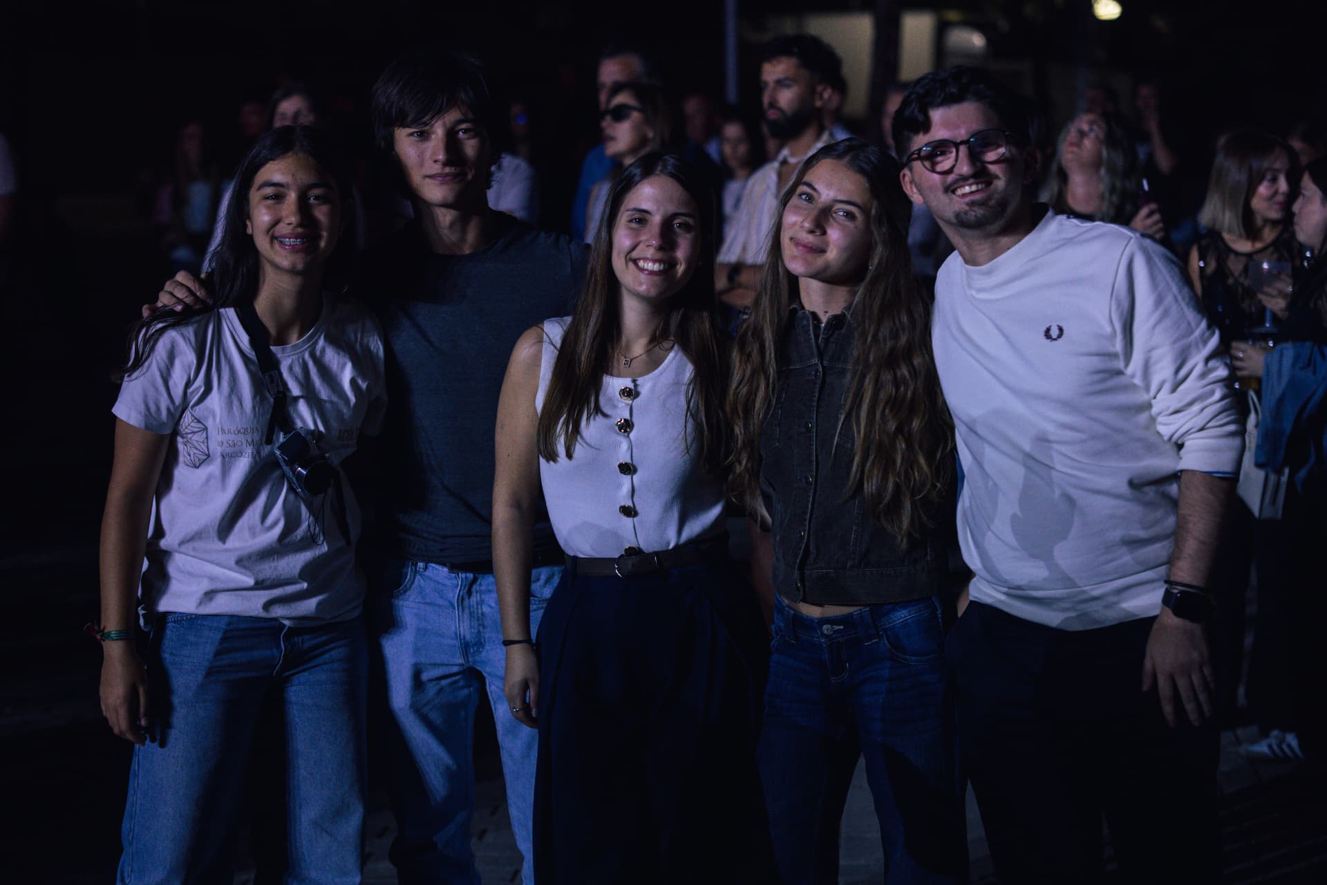 Grupo de jovens amigos sorri para a câmara à noite