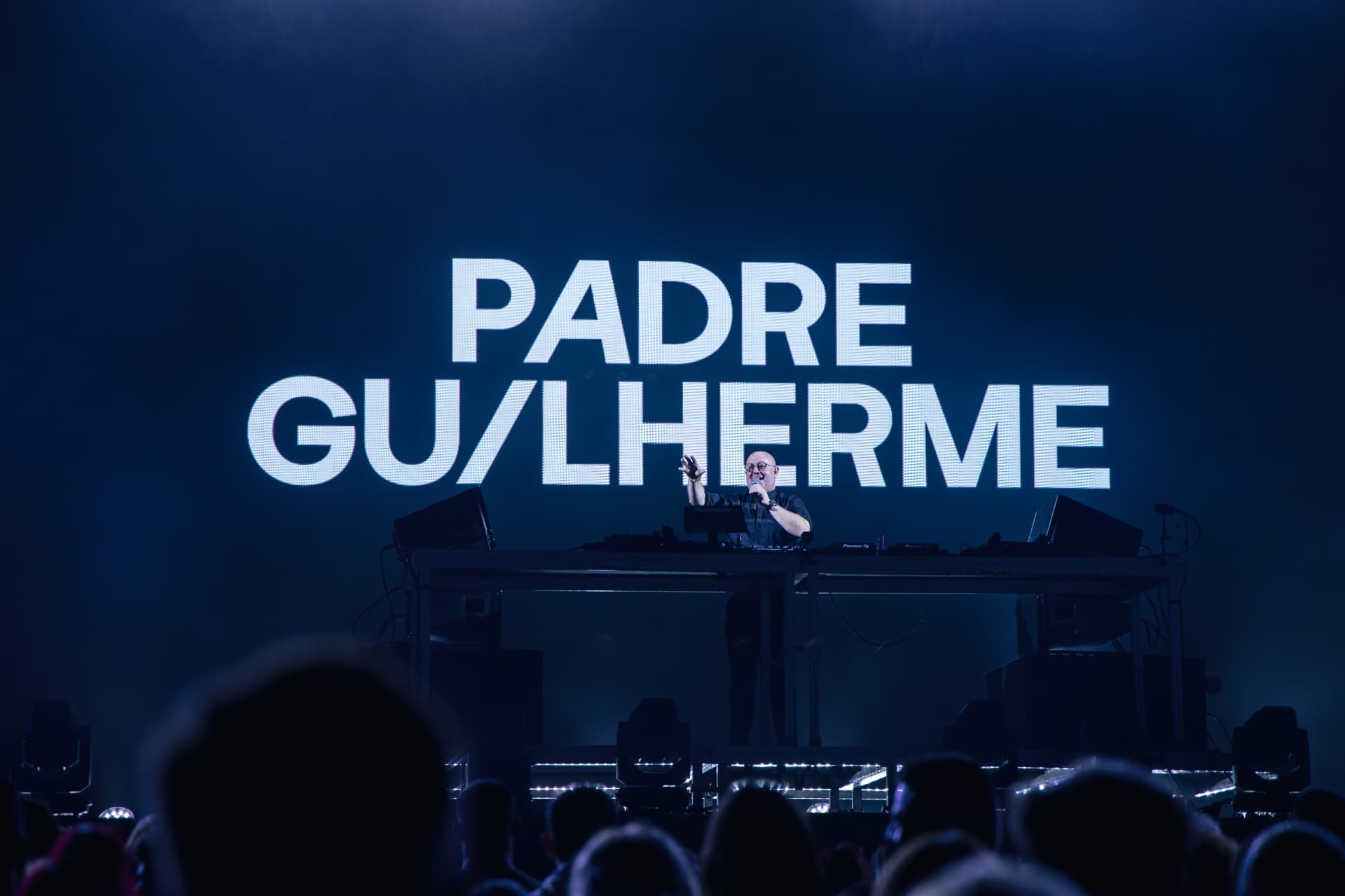 Padre Guilherme à mesa de mistura com o ecrã a anunciar a sua atuação