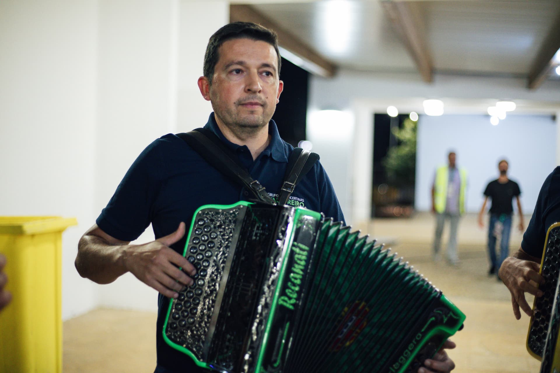 Músico com acordeão verde atravessa o corredor da Casa da Cultura