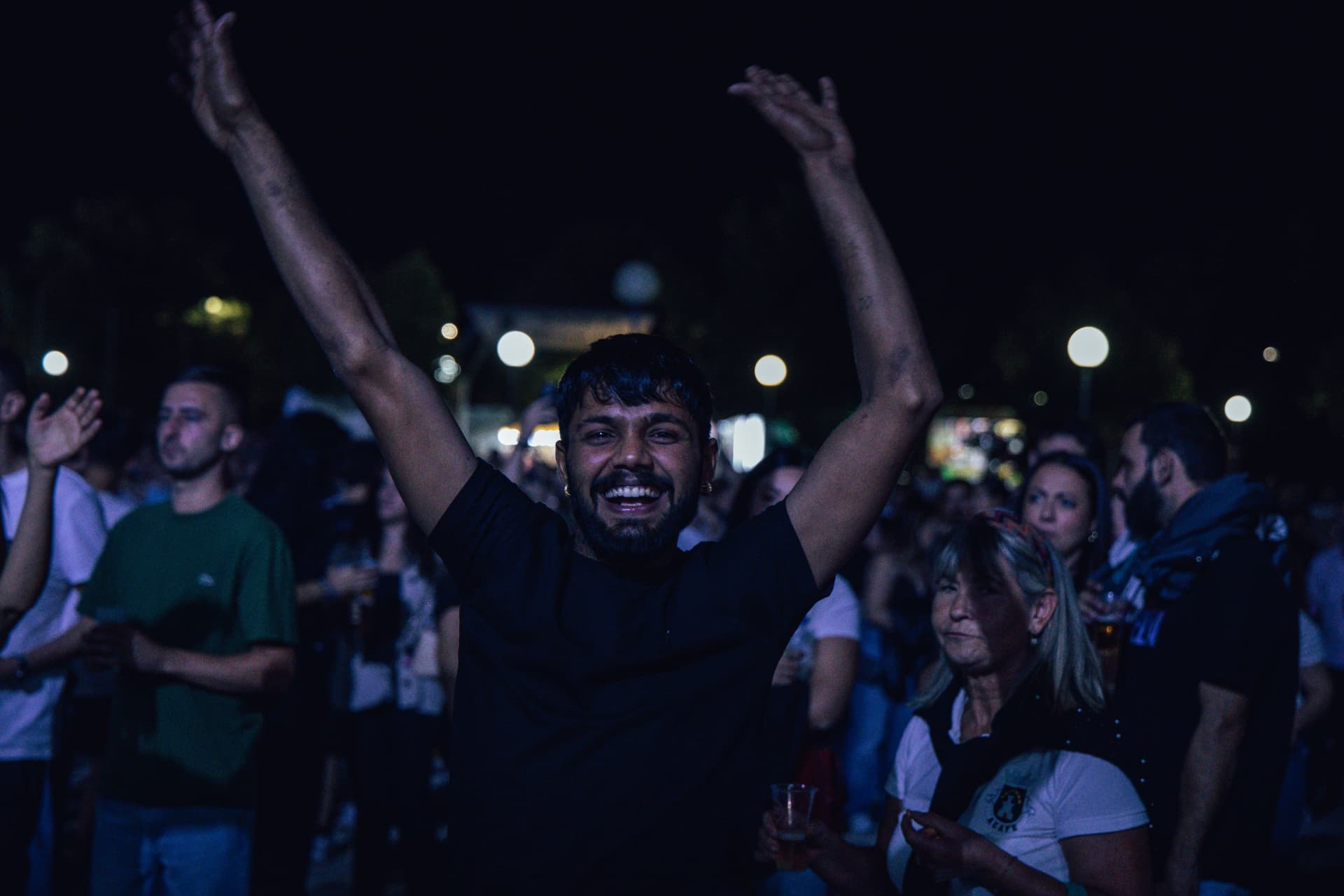 Participante de camisola preta celebra com os braços levantados