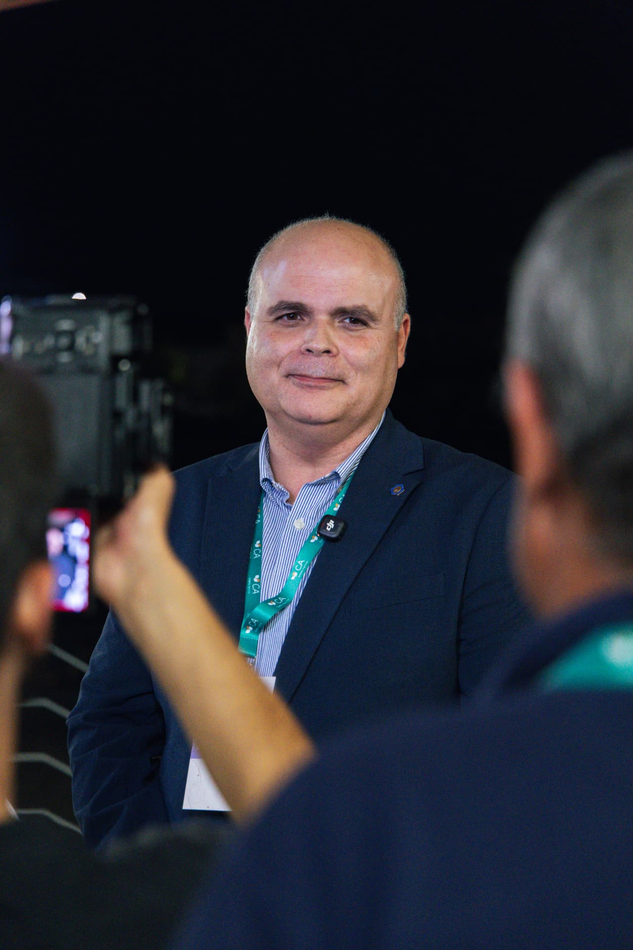Convidado sorri durante a entrevista, rodeado de câmaras