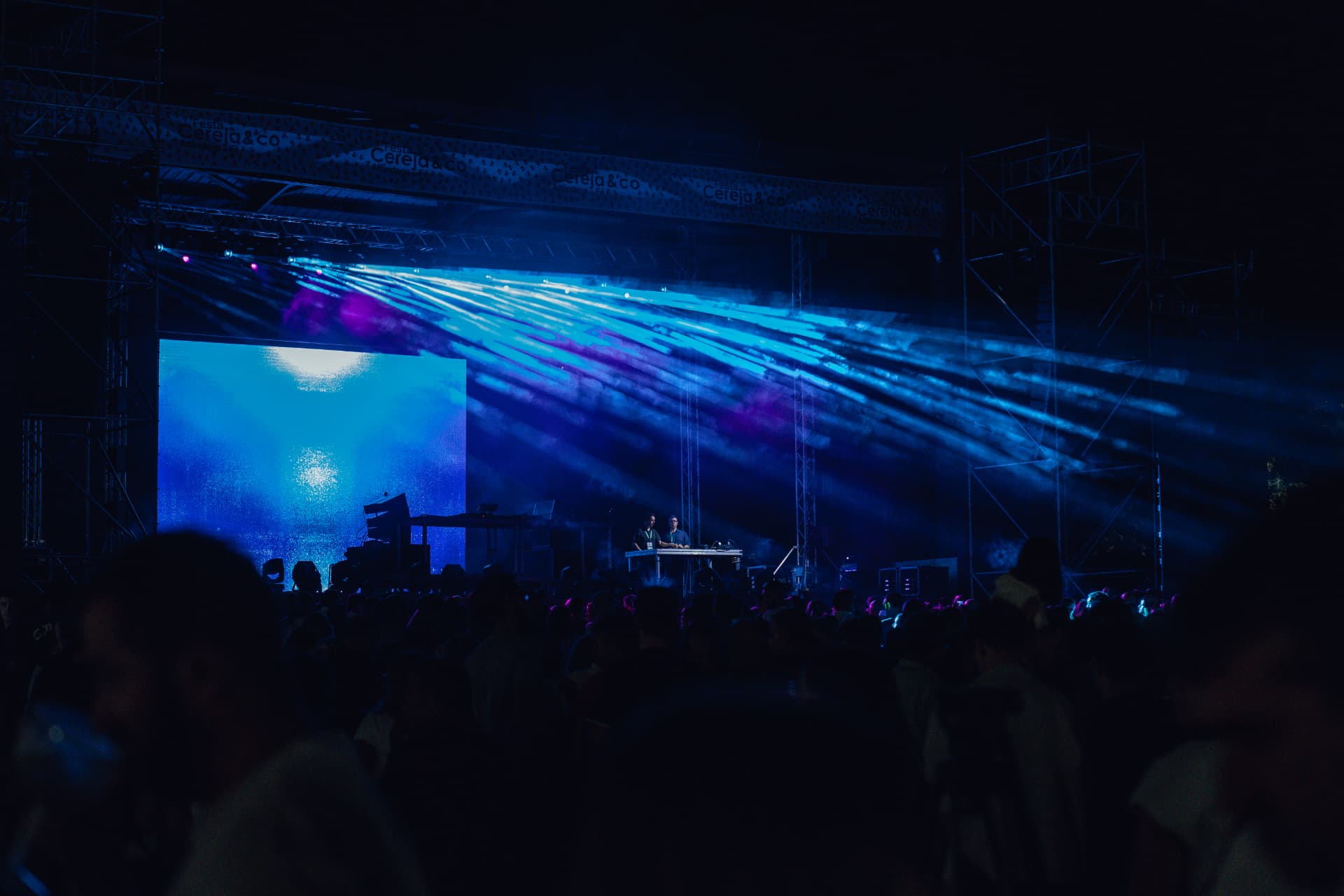 Palco com feixes de luz azul sobre a multidão