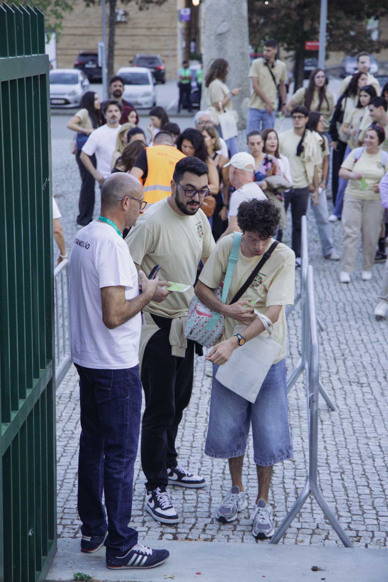 Elemento da organização conversa com jovens junto ao portão do recinto