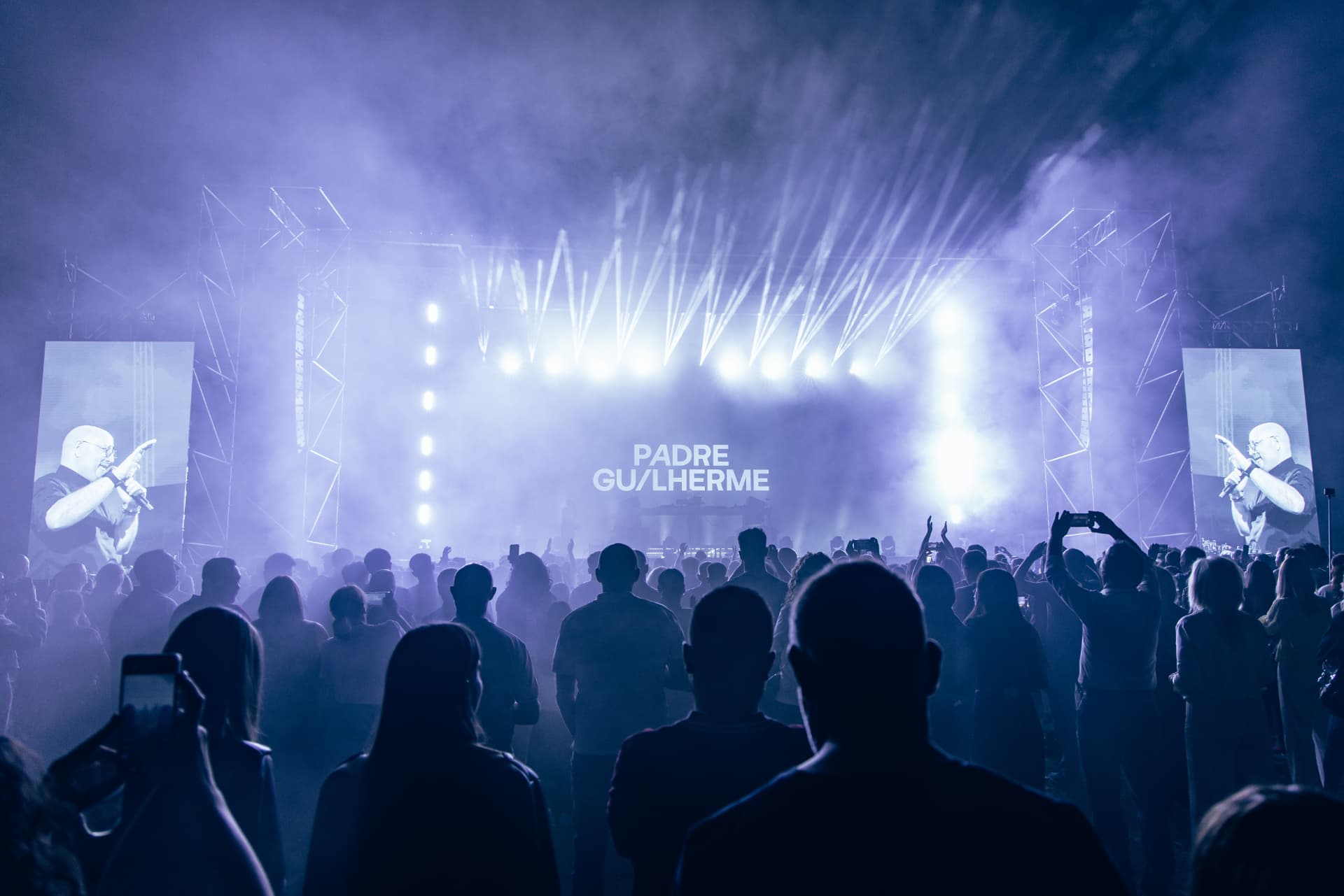 Palco com ecrãs laterais e o nome Padre Guilherme diante da multidão