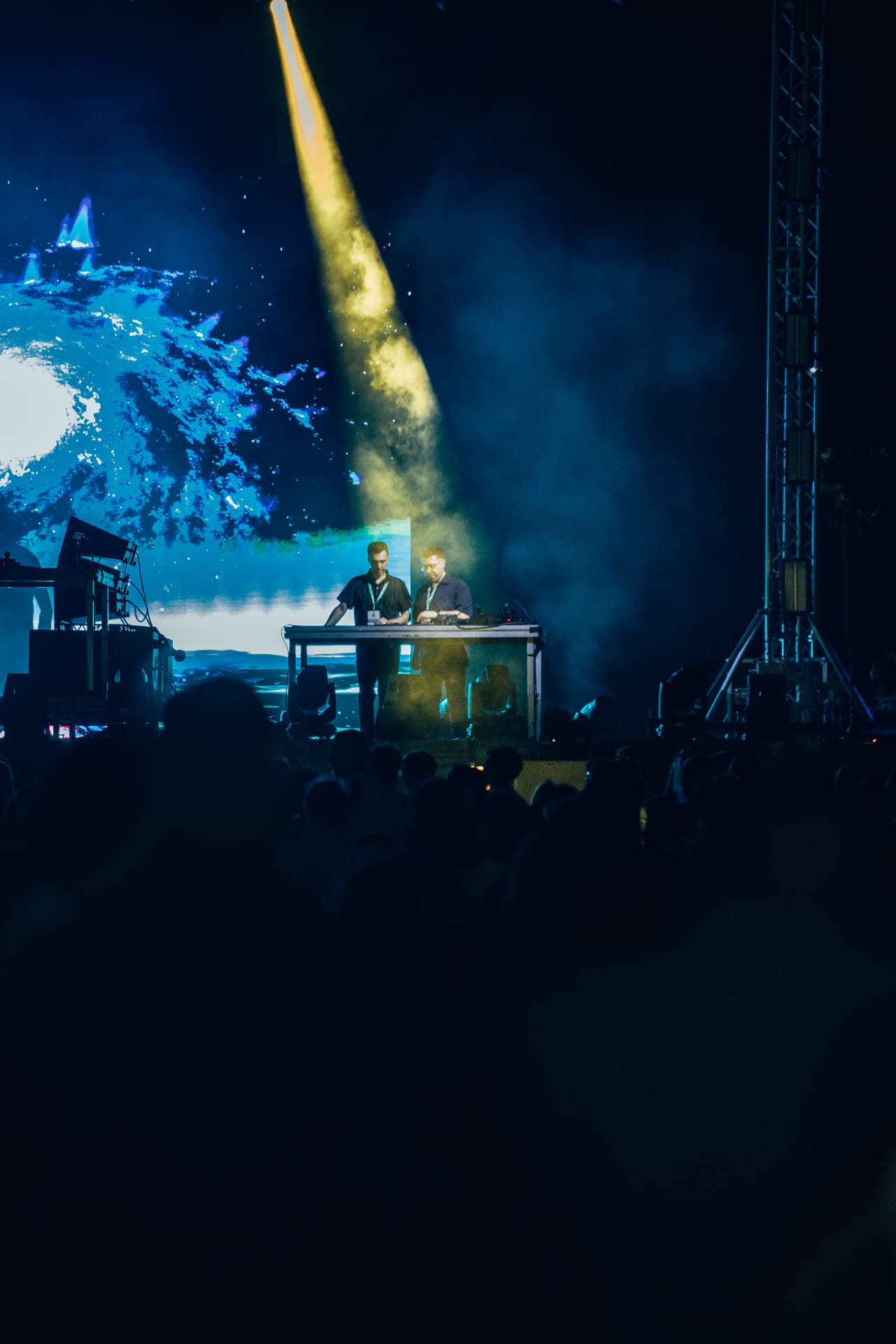 Feixe amarelo cruza o palco sobre a dupla de DJs