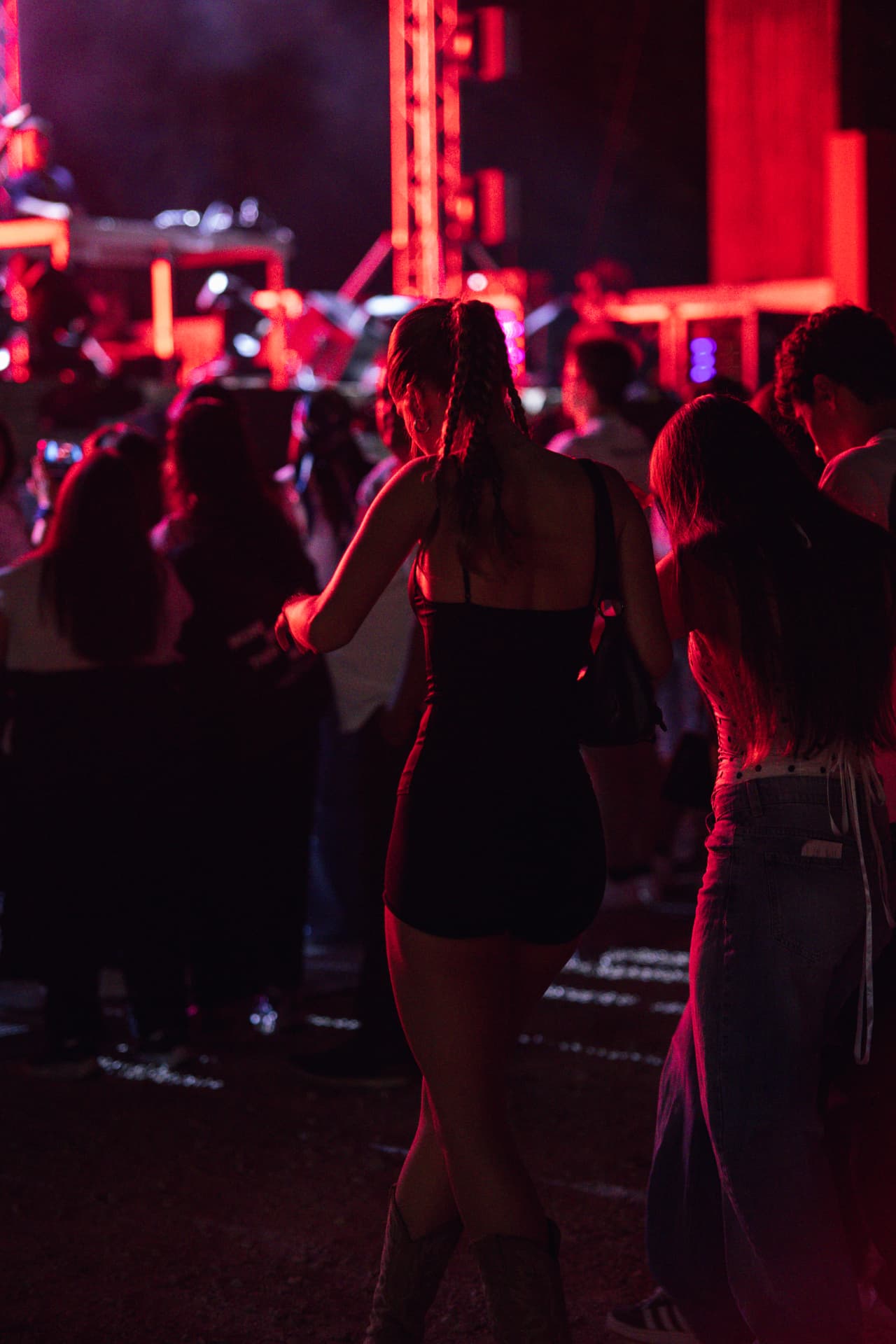 Jovens dançam no recinto sob luzes vermelhas