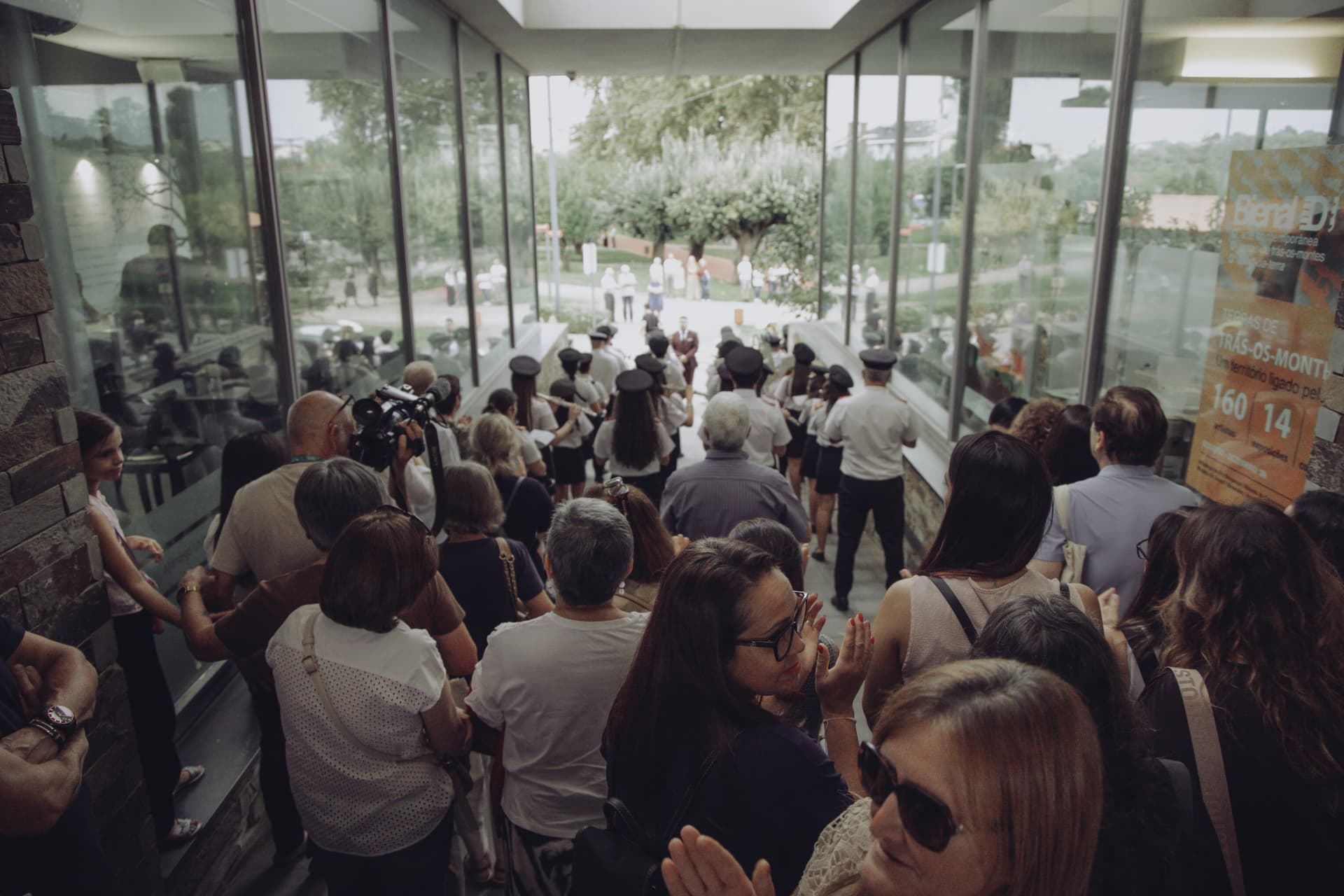Participantes acompanham a chegada da banda de música na galeria envidraçada da Casa da Cultura Mestre José Rodrigues
